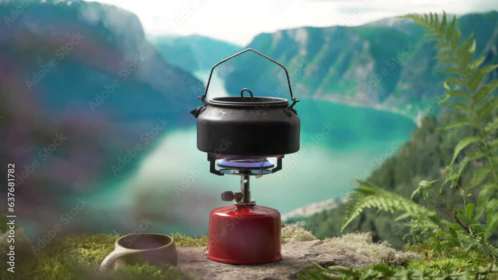 Cooking, making coffee or tea on a portable camping gas burner with a red gas cylinder with scandinavian nature background. Summer hiking, ecotourism, survival. Cooking, making coffee or tea on a portable camping gas burner with a red gas cylinder with scandinavian nature background. Summer hiking, ecotourism, survival.