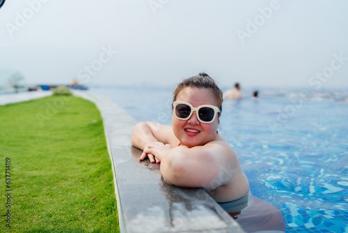 Overweight young asian woman wearing swimsuit relaxing in the pool Happy plus size woman cheery funny Vacation Traveling in summer.