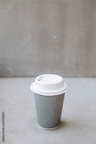 Portrait or vertical and selective focus shot of a cup of coffee on a disposable paper cup in a industrial cafe or coffee shop on isolated grey background