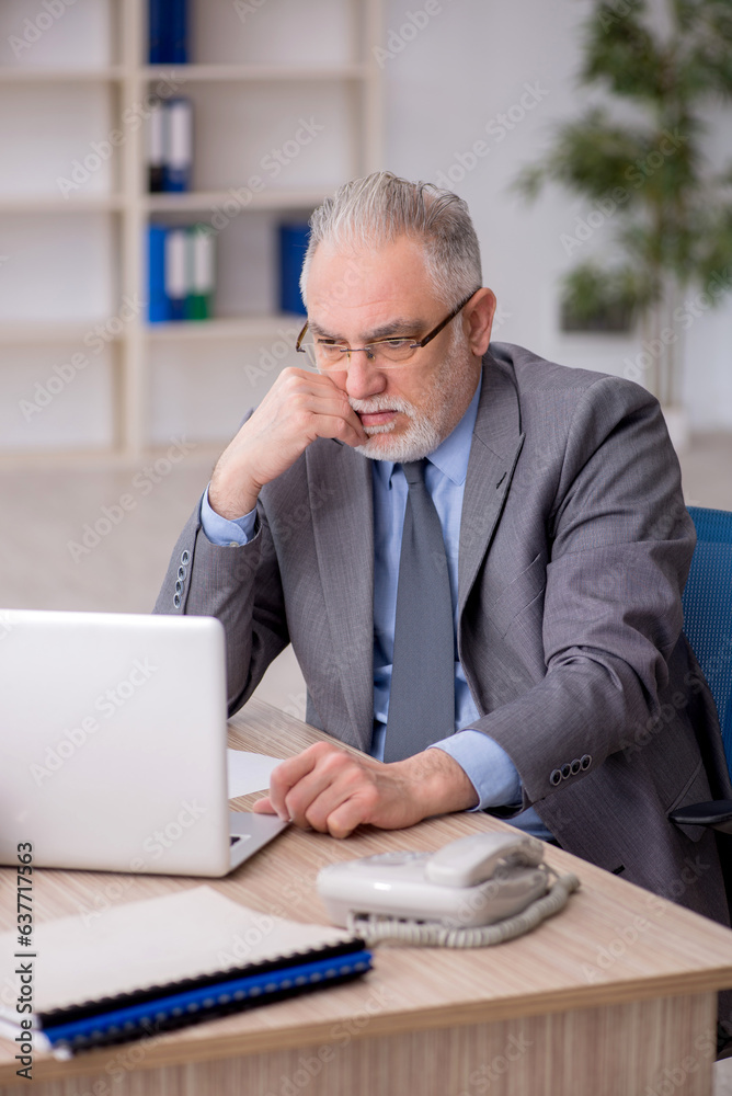 Old male employee working in the office Old male employee working in the office