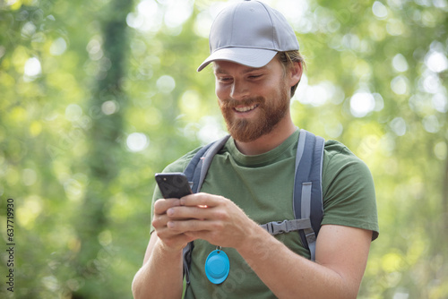 cheerful man hiker using smartphone in forest