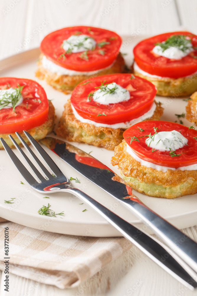 Fried zucchini in batter with creamy garlic sauce and fresh tomatoes close-up in a plate on the table. Vertical