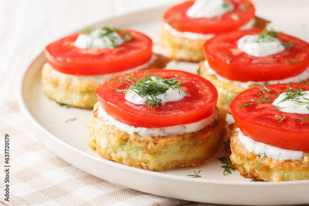 Pan fried zucchini in egg batter served with fresh tomato and creamy sauce close-up in a plate on the table. Horizontal Pan fried zucchini in egg batter served with fresh tomato and creamy sauce close-up in a plate on the table. Horizontal