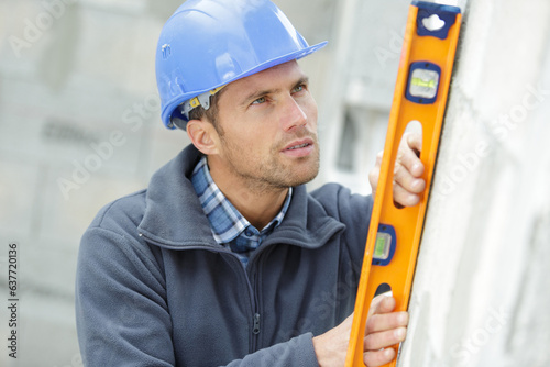 builder in helmet is measuring wall