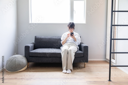 ソファーでスマホを操作する女性 woman operating a smartphone