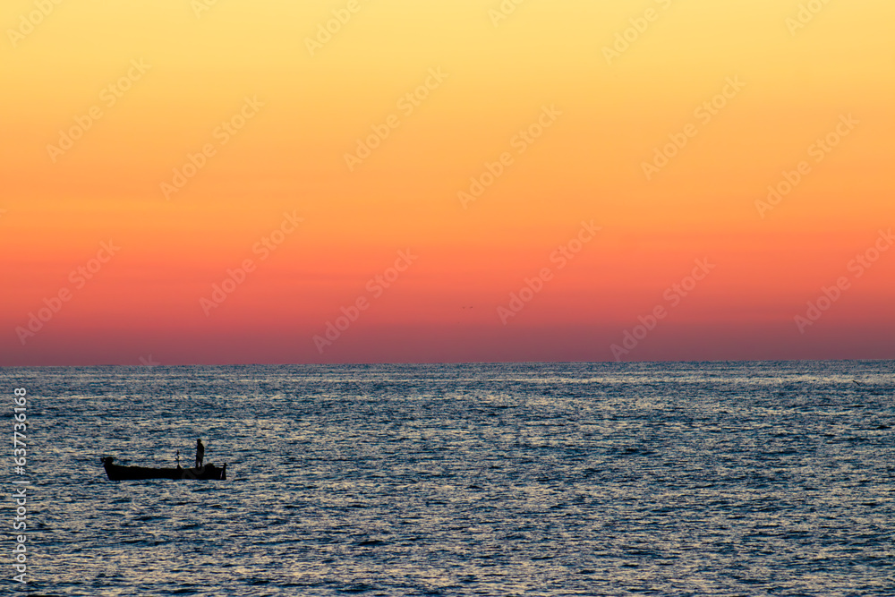 Scenic view of sunset orange sky in peaceful sea bay with silhouette of lonely kayak. Trabzon,Turkey