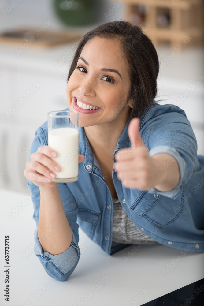 woman holding glass of milk and making thumbs-up gesture