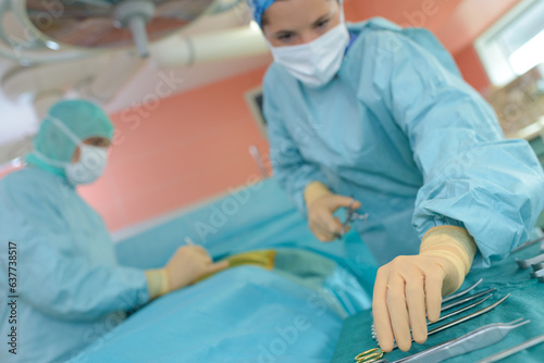 medical worker reaching for instrument during operation