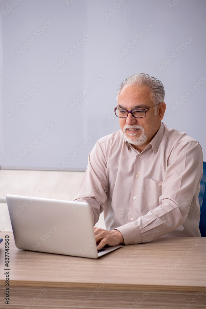 Old male teacher in front of whiteboard