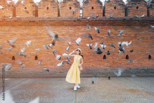 Young asian woman traveler in Yellow dress with hat and bag traveling on Tha Pae Gate, Tourist visit at the old city in Chang Mai, Thailand. Asia Travel, Vacation and summer holiday concept photo