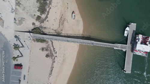 An aerial view captures an empty ferry after disembarking tourists, as gentle waves shimmer in the sunlight, painting a serene maritime tableau.