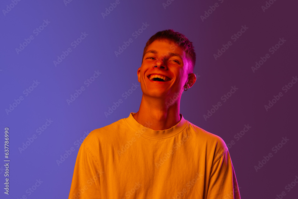 Portrait of young guy cheerfully laughing against gradient purple background in neon light. Happiness and joy. Concept of human emotions, youth, lifestyle, fashion, facial expressions, ad Portrait of young guy cheerfully laughing against gradient purple background in neon light. Happiness and joy. Concept of human emotions, youth, lifestyle, fashion, facial expressions, ad