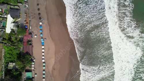 Batu Belig Beach Coastline with Long Foamy Waves Rolling Over Soft Sand In Bali Indonesia - aerial top down flyover along shore photo