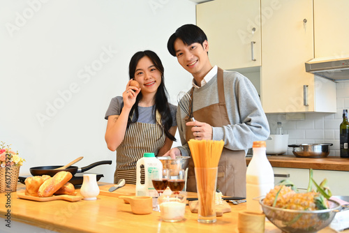 Beautiful young couple standing at worktop in the kitchen preparing and preparing breakfast together.