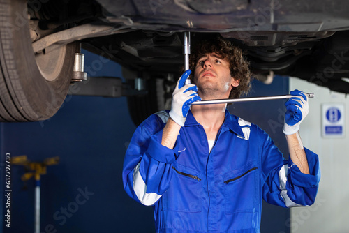 mechanic using ratchet wrench and fixing underneath the car photo