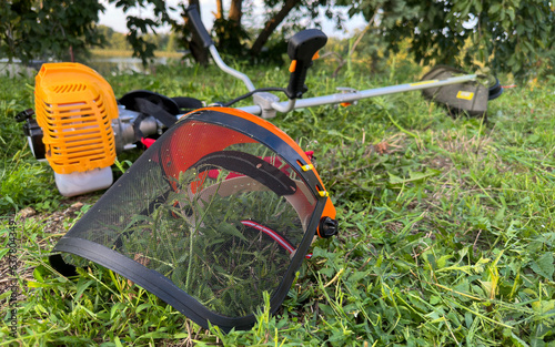 Cutting grass with brushcutter. Protective visor for lawn mowing. Autumns lawn mowing with protective clothes.