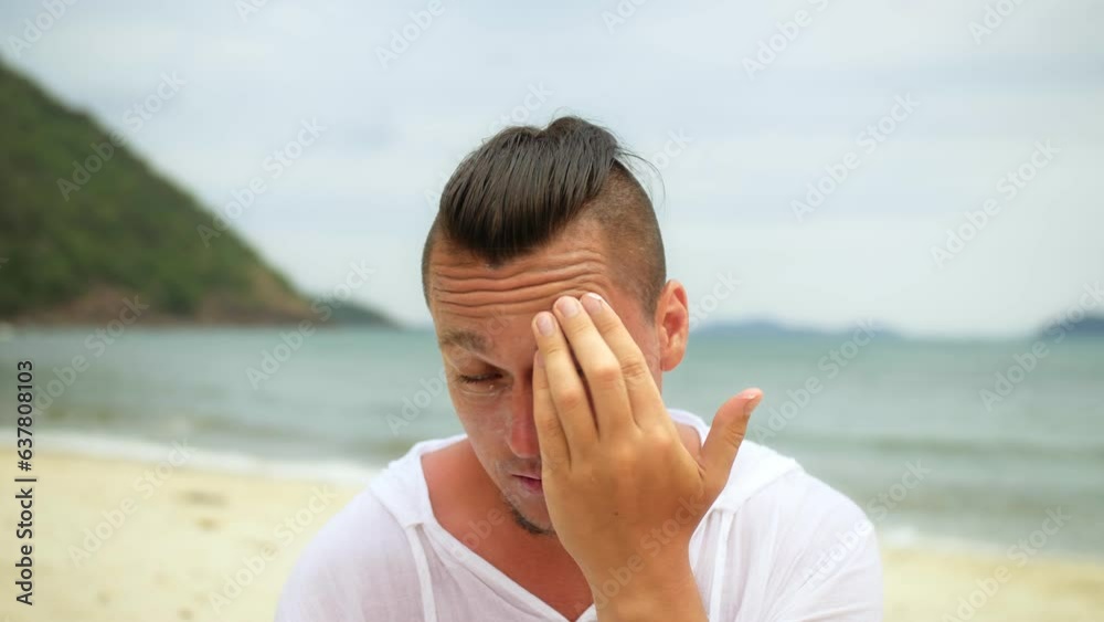 Man looking at camera, relax on beach near sea smearing sunscreen cream on face.Portrait man apply sun cream protection lotion.Concept facial beauty skin care, moisturizer cosmetic, hygiene treatment Man looking at camera, relax on beach near sea smearing sunscreen cream on face.Portrait man apply sun cream protection lotion.Concept facial beauty skin care, moisturizer cosmetic, hygiene treatment