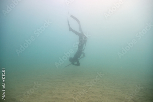 Anonymous diver with harpoon diving into sea
