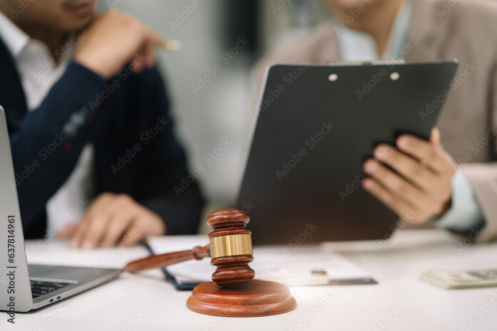 Close up view of auction hammer on the desk in lawyer office and lawyer writing document as courtroom. Close up view of auction hammer on the desk in lawyer office and lawyer writing document as courtroom.