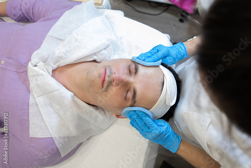 top view of a beautician performing facial cleansing on a man