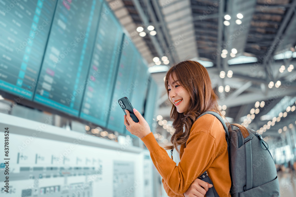 Happy asian woman traveller checking flight schedule departures board ...