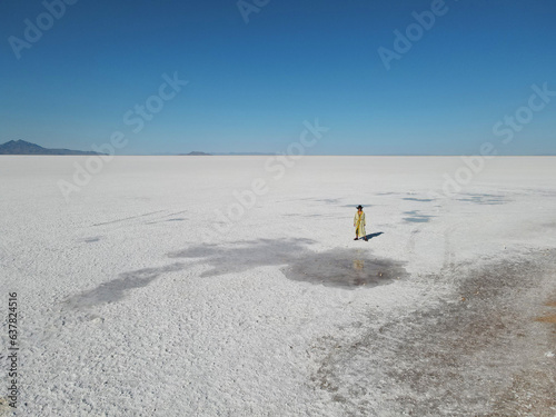 The view of Bonneville salt flats from the drone and a woman standing in the middle of it.