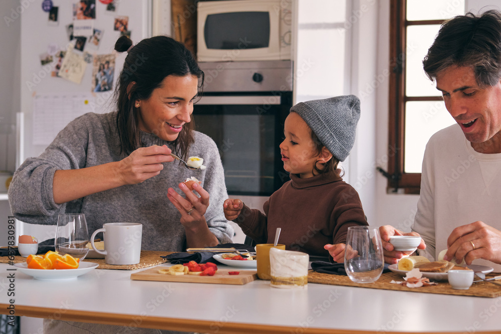 Crop family with little daughter during breakfast at home Crop family with little daughter during breakfast at home