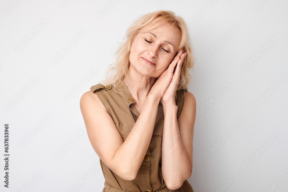 Studio portrait blonde adult woman put palms under head pretending to sleep isolated on white background Studio portrait blonde adult woman put palms under head pretending to sleep isolated on white background
