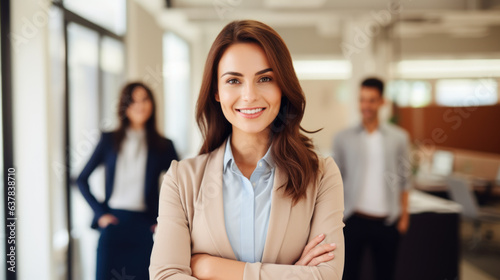 Beaming and alluring self-assured female professional showcasing herself at her corporate workspace, surrounded by fellow team members and staff members.