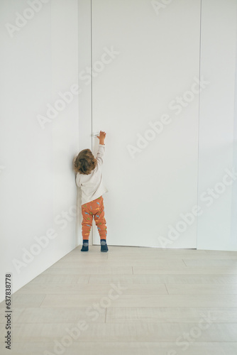 Unrecognizable toddler reaching for doorknob at home
