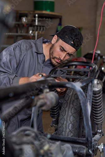 Serious male mechanic fixing motorbike in garage