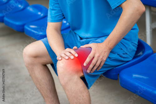 Diseases of the knee joint, bone fracture and inflammation, athletic man on a sports ground after workout suffering from pain in leg and doing self-massage