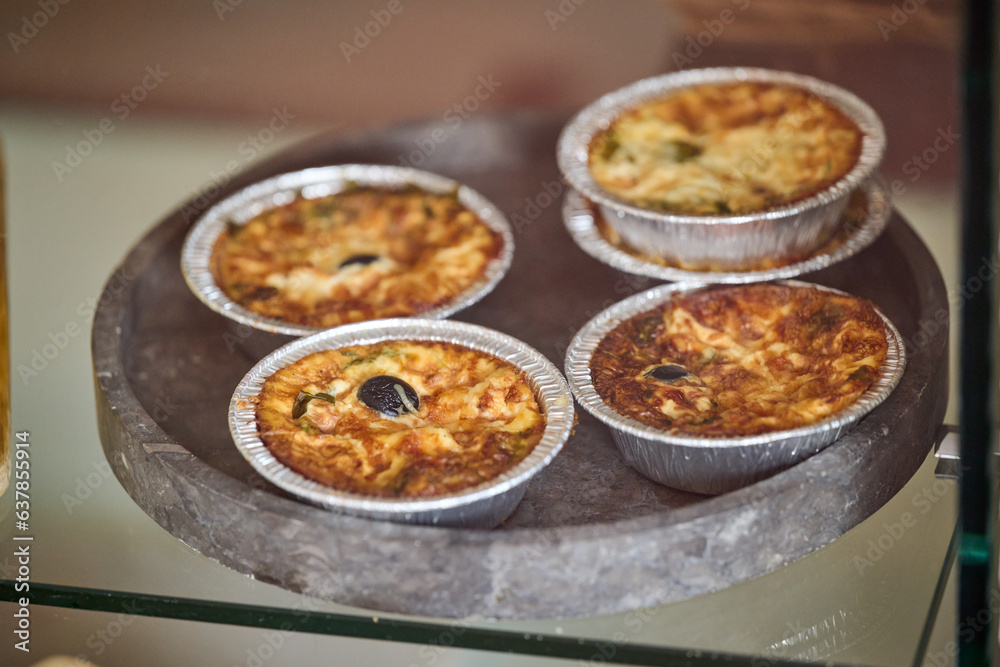 Small vegetarian quiche with olive and cheese on stone plate Small vegetarian quiche with olive and cheese on stone plate