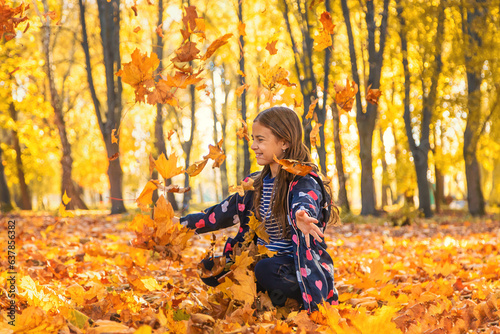 Autumn child in the park with yellow leaves. Selective focus.