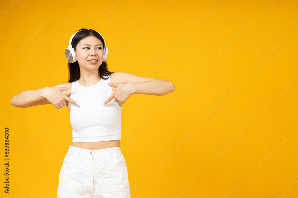 Beautiful asian girl in headphones pointing to t-shirt. Beautiful asian girl in headphones pointing to t-shirt.
