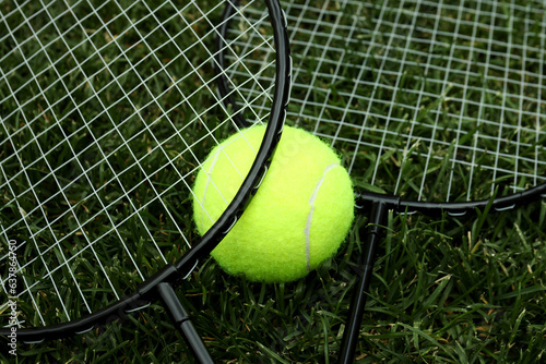 Badminton rackets and tennis ball on green grass