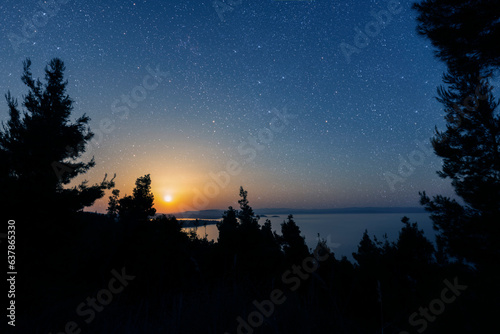 a night sea with a view of mountains and starry sky