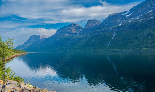 Beautiful rocky hill with waterfall above sea fjord