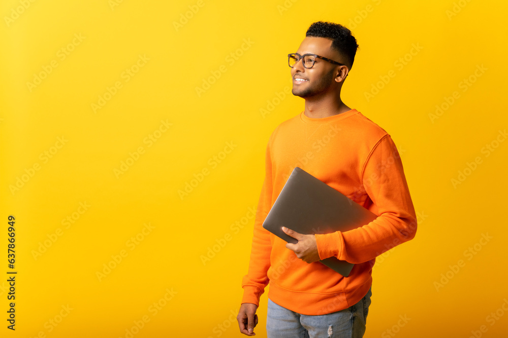 Inspired indian male office employee or student carrying laptop isolated on plain yellow color, handsome arab man full of new ideas looking aside thoughtfully, start-up owner Inspired indian male office employee or student carrying laptop isolated on plain yellow color, handsome arab man full of new ideas looking aside thoughtfully, start-up owner