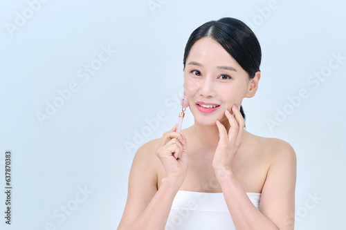 Wallpaper Mural 아시아 한국의 검은머리의 젊은 여자 모델이 끈 나시를 입고 핑크색 마사지 롤러를 얼굴에 대고 포즈를 취하고 있다.    Torontodigital.ca