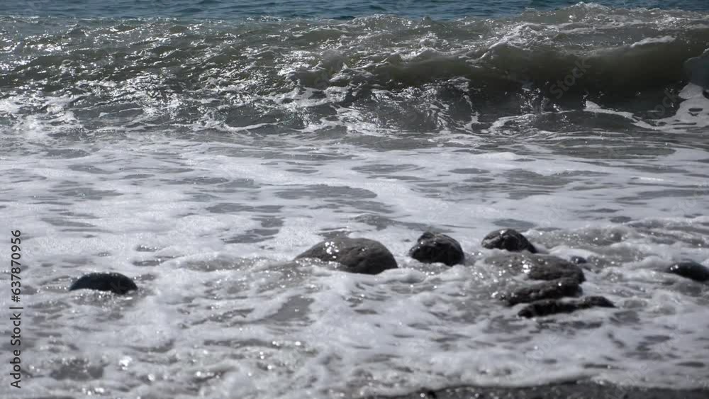 Ocean waves crush the pebble rocks of the beach. Slow motion shooting in 4K format of sea waves crashing on the shore. Splashes of sea storm water, foam. Giant waves are crashing on the coastal rocks. Ocean waves crush the pebble rocks of the beach. Slow motion shooting in 4K format of sea waves crashing on the shore. Splashes of sea storm water, foam. Giant waves are crashing on the coastal rocks.