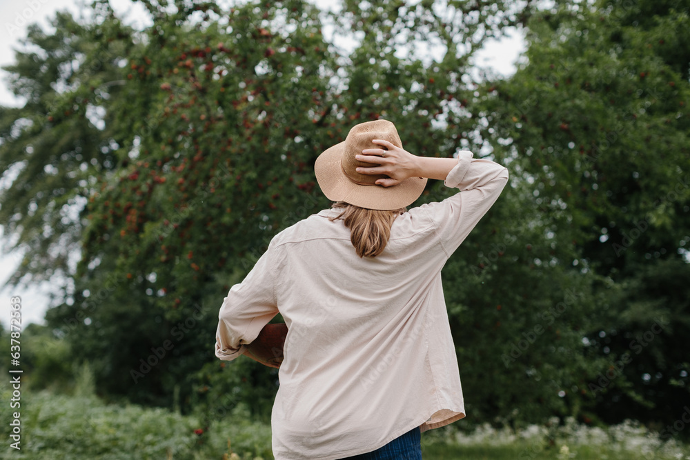 Girl farmer in the orchard. Rear view.