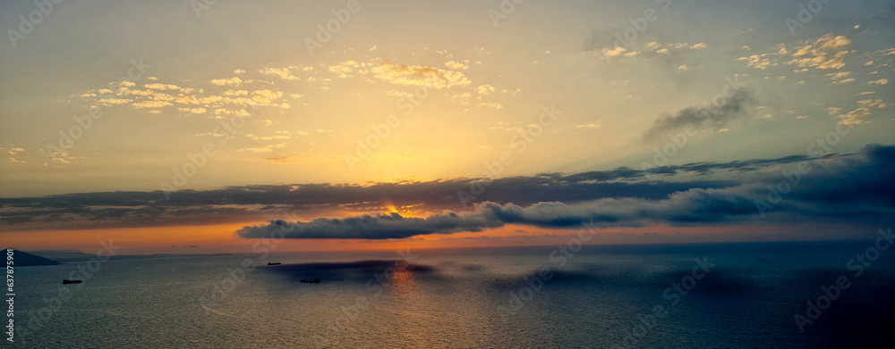 A panoramic  view of 
sunset above the mediterranean sea during the golden hour with sun hidden by clouds.Overlooking view of the the mediterranean sea during sunset in Canastel forest Oran Algeria