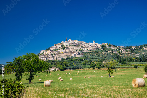 Panoramic view of the beautiful village of Trevi, in the province of Perugia, Umbria, Italy. The ancient stone houses of the city, perched on the hill. A field with freshly harvested hay bales.
