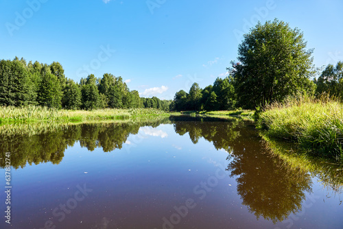 Fototapeta Naklejka Na Ścianę i Meble -  Beautiful summer riverbank at sunny day with reflection in the water