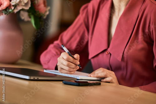 Close-up image of the female person writing on a notepad.