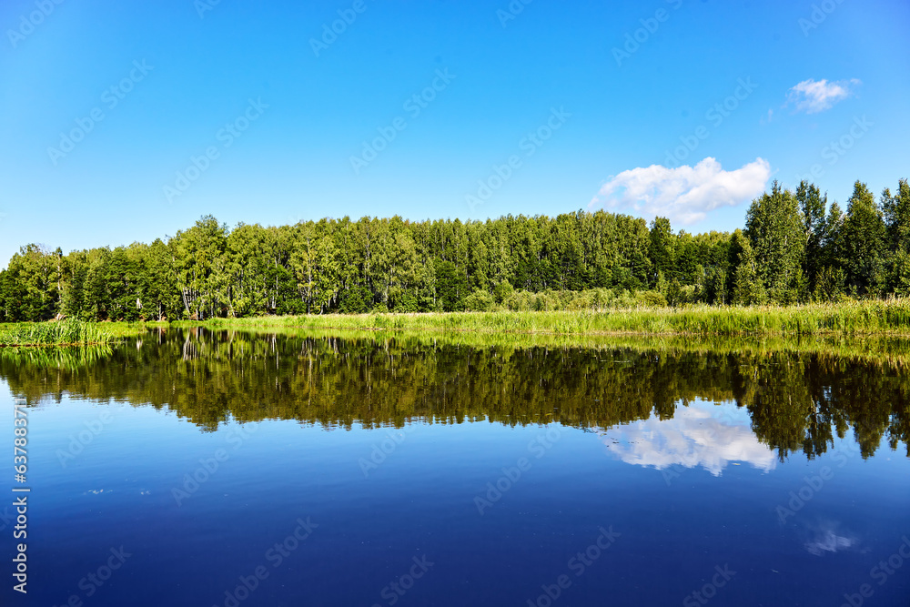Beautiful summer riverbank at sunny day with reflection in the water