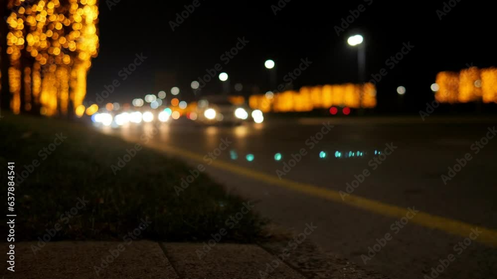 A blurry image of cars on the road with garlanded trees. Bokeh. City road with golden flashing lights. The trees are covered with many golden lights in the evening. A blurry image of cars on the road with garlanded trees. Bokeh. City road with golden flashing lights. The trees are covered with many golden lights in the evening.