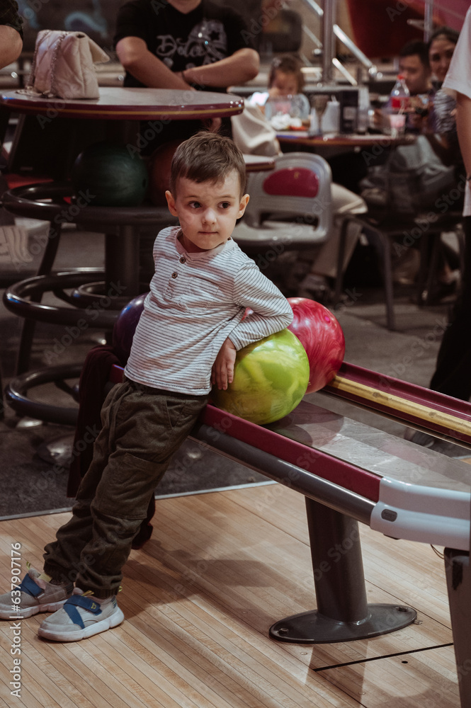 Fototapeta premium little child boy playing bowling in club