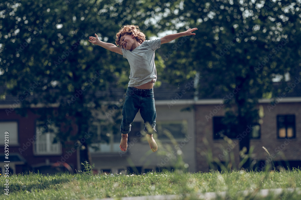 Cheerful boy jumping in meadow in countryside
